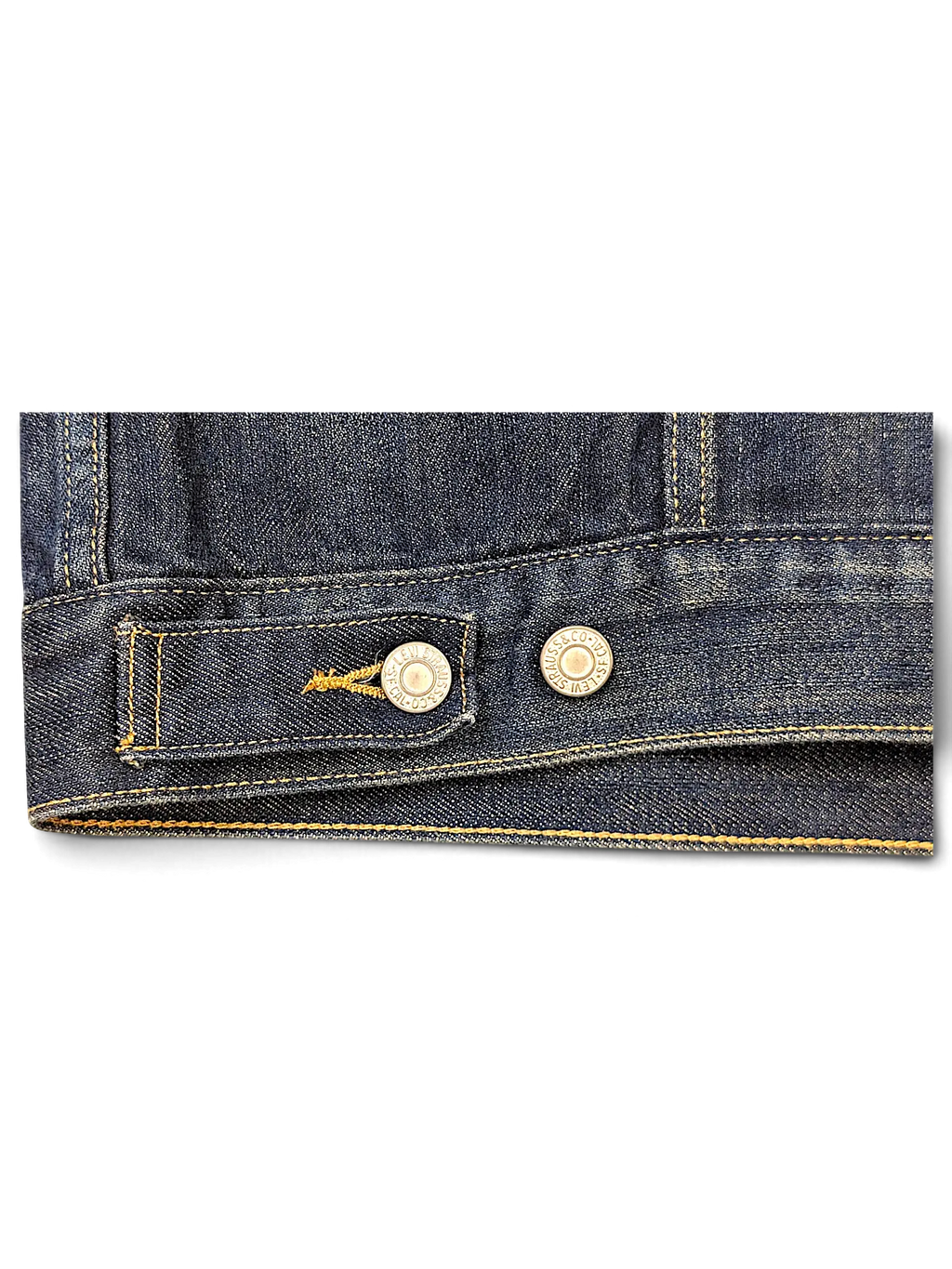 Close-up of the hem and metal button detail on a dark blue denim vest from JAKE & IPI
