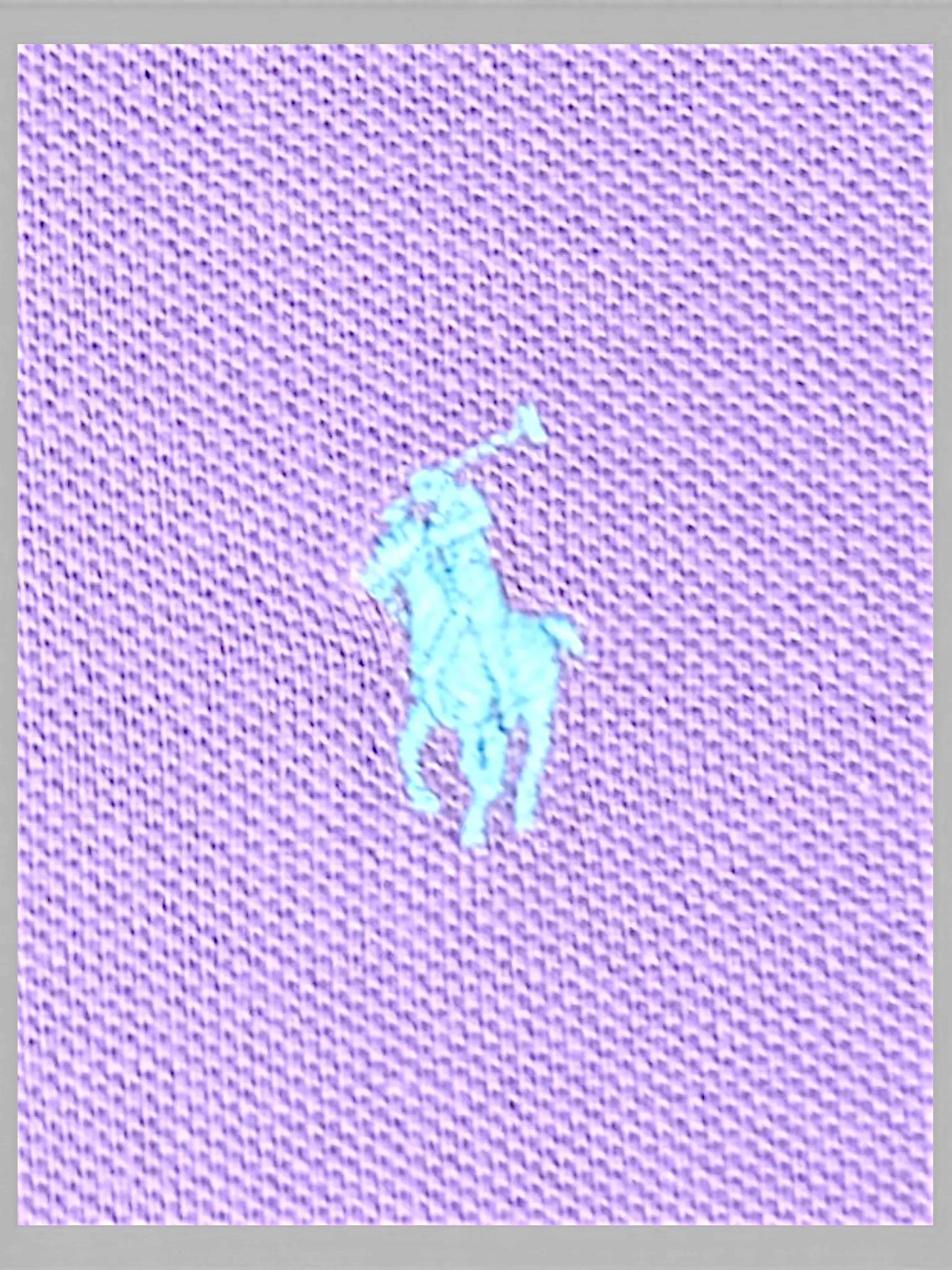 Close-up of JAKE & IPI lilac polo shirt fabric featuring an embroidered light blue polo player logo
