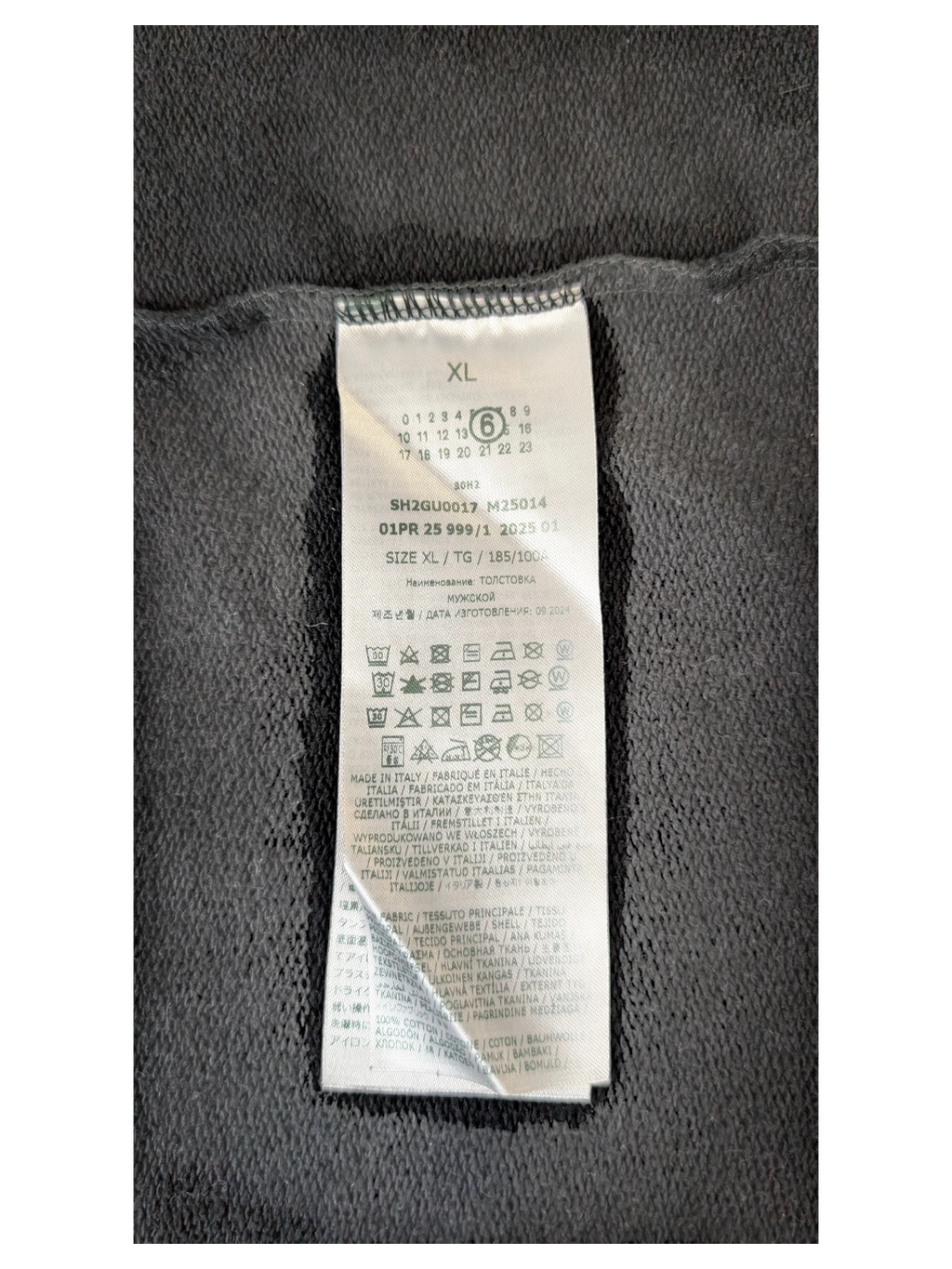 JAKE & IPI MM6 Lunar New Year clothing care label with size XL and Italian manufacturing details on dark fabric