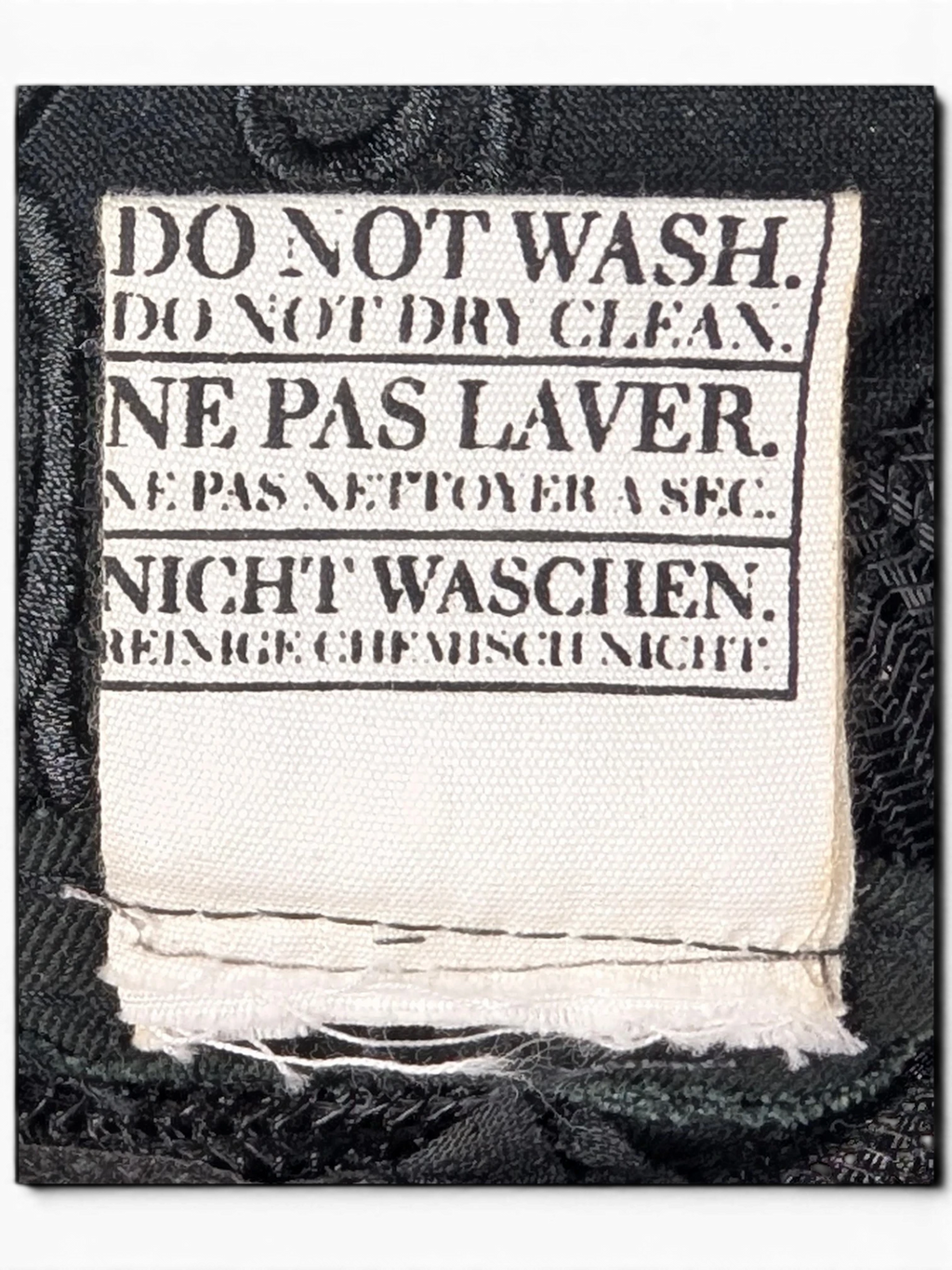 JAKE & IPI IBE Morivelle cap fabric care label with do not wash and do not dry clean instructions in three languages