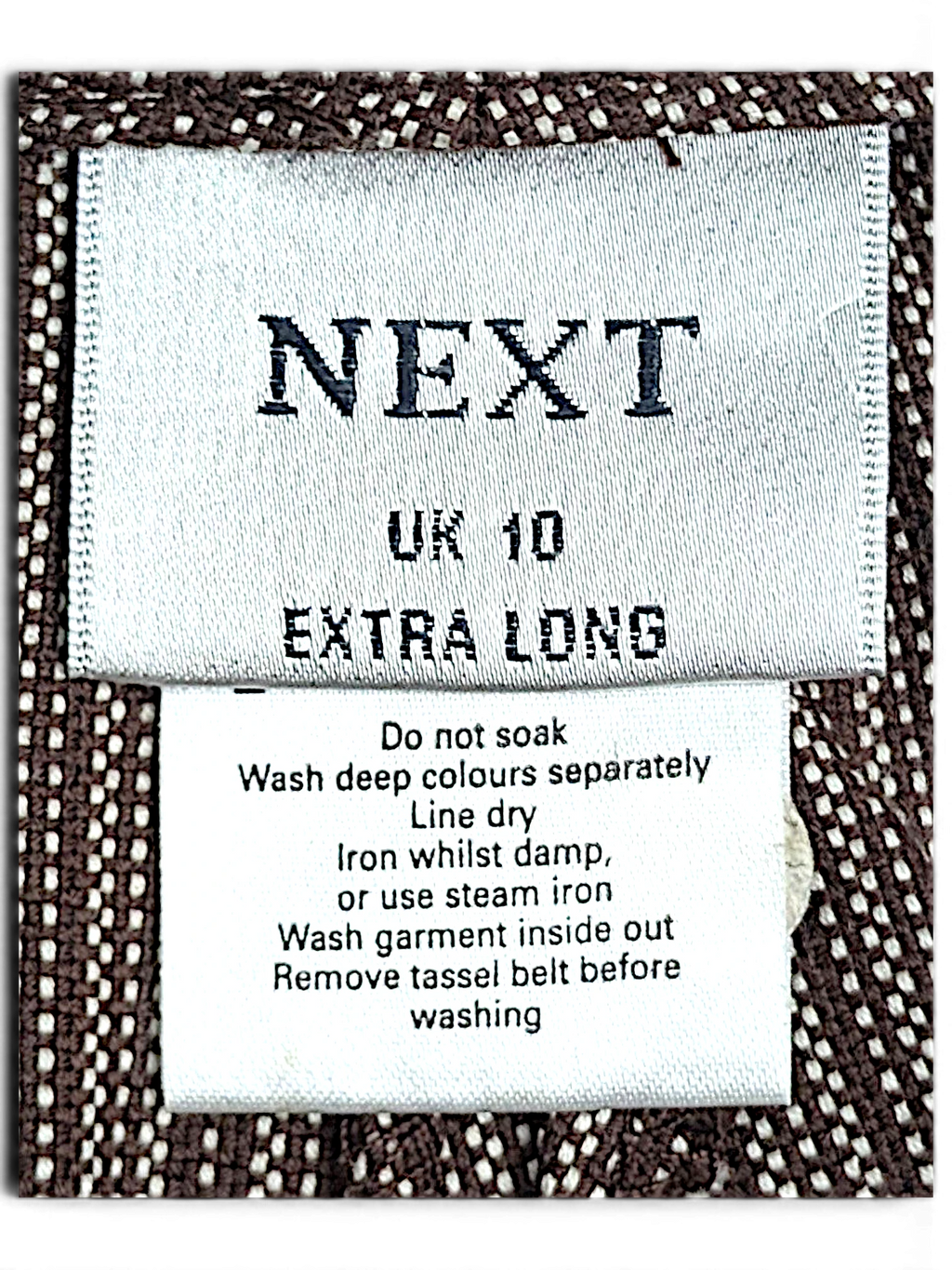 JAKE & IPI Next brand clothing label on brown and cream pinstripe cotton fabric with care instructions