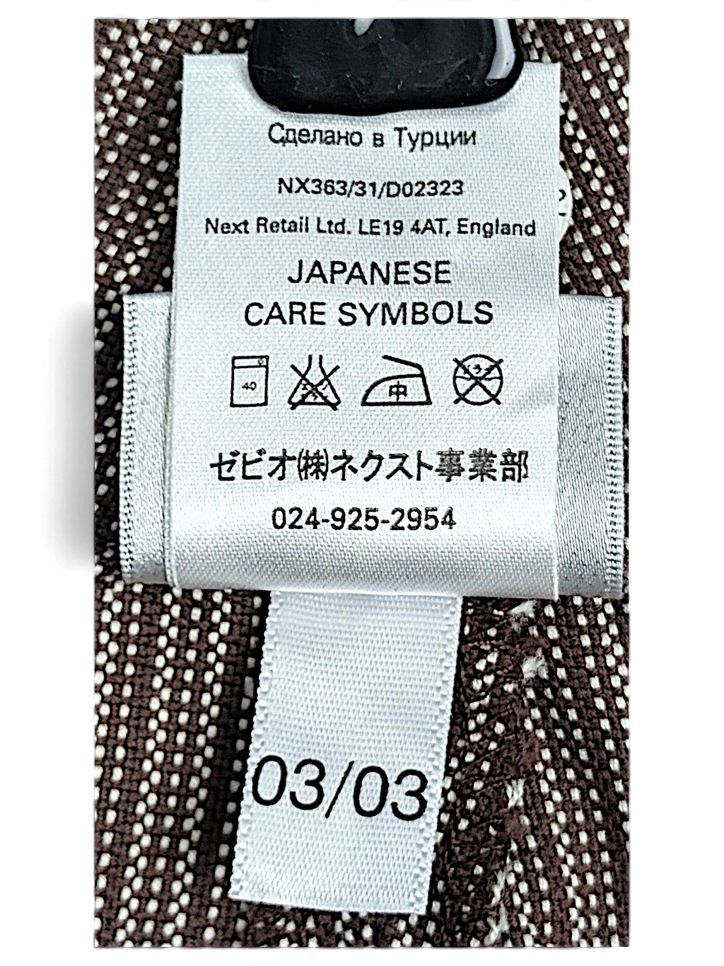 JAKE & IPI Next trousers care label with Japanese symbols and fabric details on brown pinstripe cotton