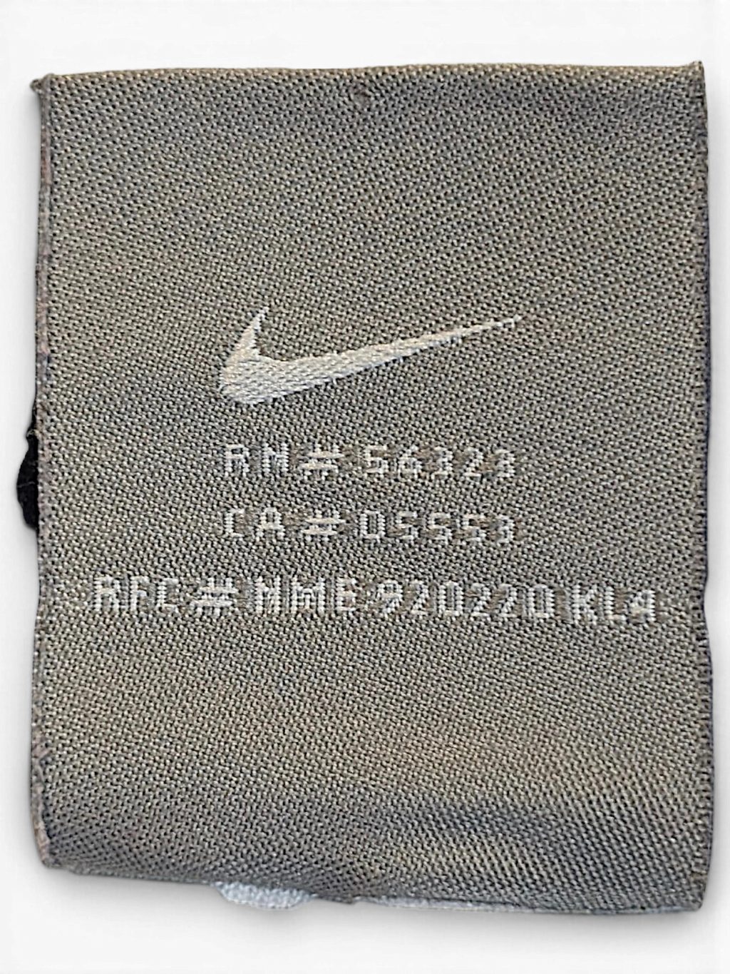JAKE & IPI Nike brand clothing label with Swoosh logo and RN number on grey fabric