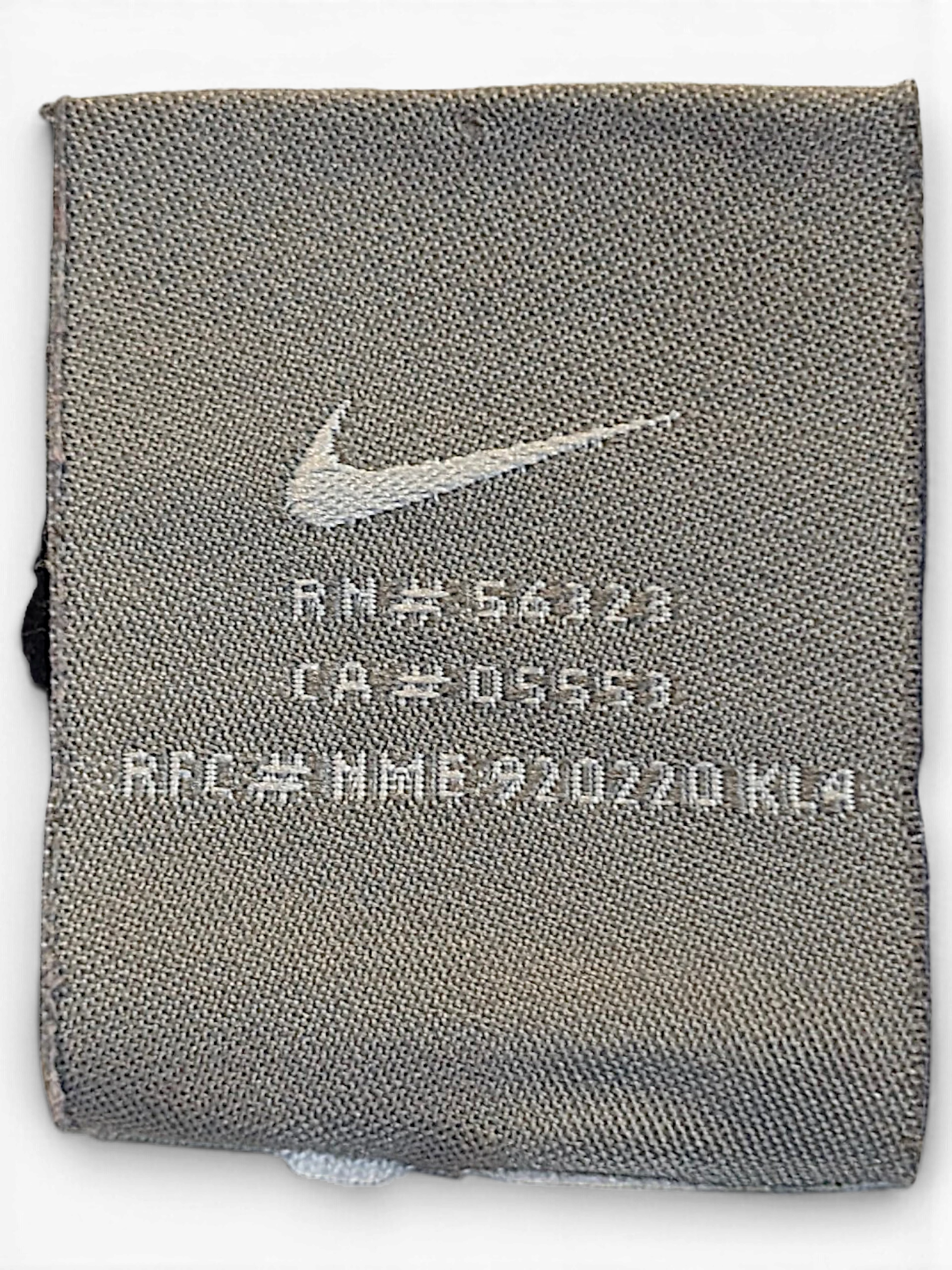 JAKE & IPI Nike brand clothing label with Swoosh logo and RN number on grey fabric
