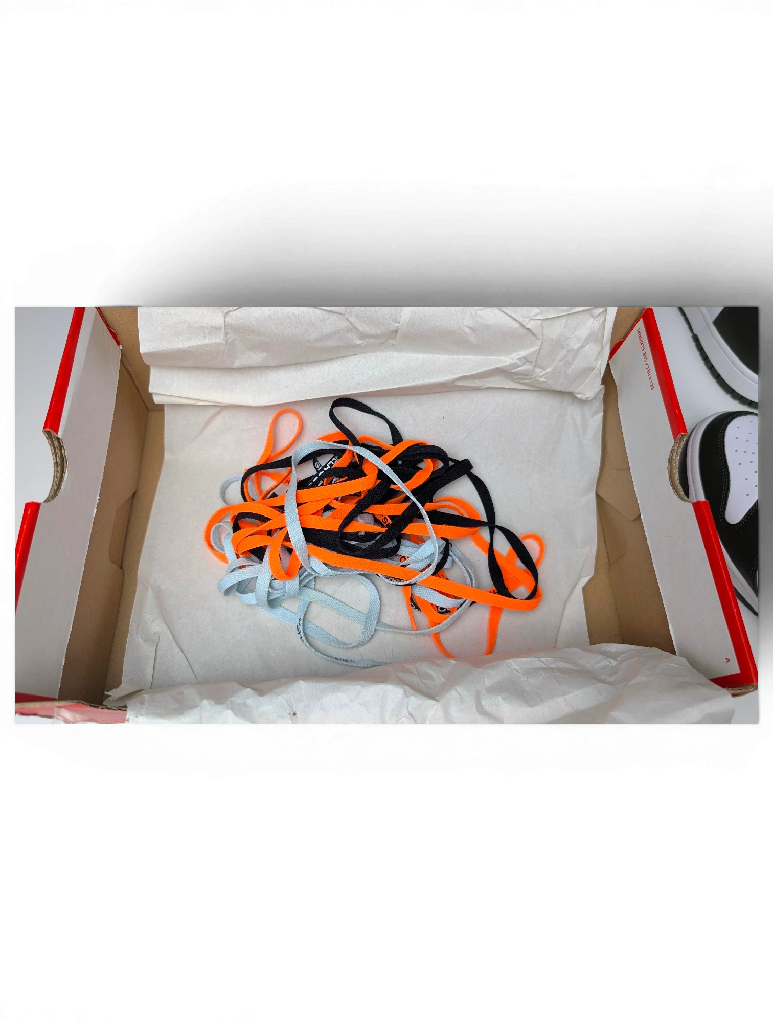 JAKE & IPI Nike Dunk High Cargo Khaki sneaker laces in orange, black, and light blue inside a shoe box.