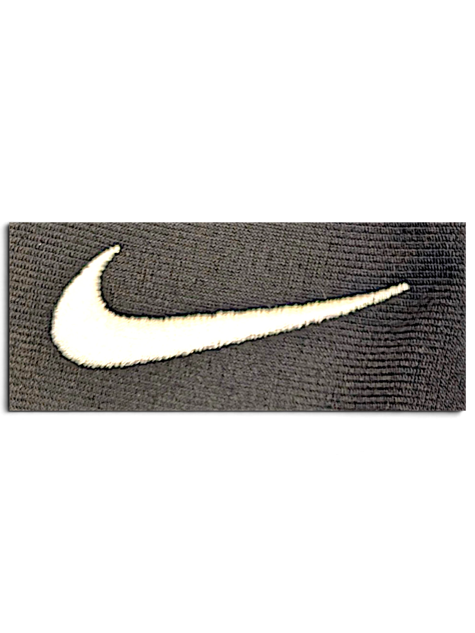 Close-up of a white embroidered Nike Swoosh logo on grey polyester fabric from JAKE & IPI track pants