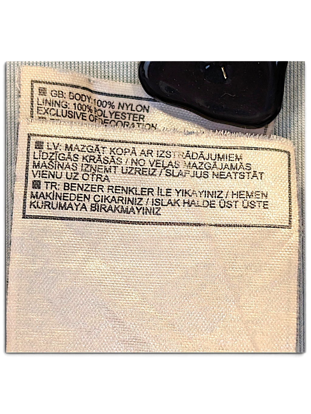 JAKE & IPI Nike track pants care label showing 100% nylon body and 100% polyester lining composition details.