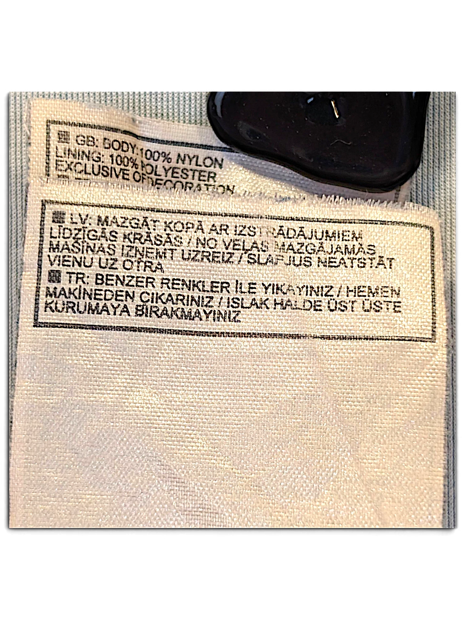 JAKE & IPI Nike track pants care label showing 100% nylon body and 100% polyester lining composition details.