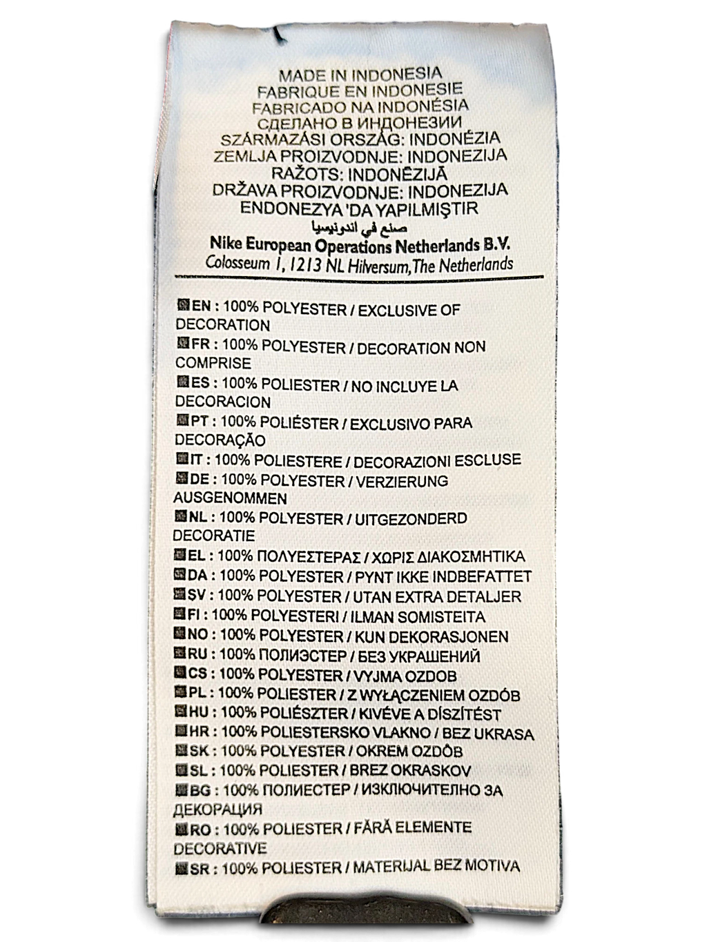 JAKE & IPI Nike track pants care label showing 100% polyester composition in multiple languages