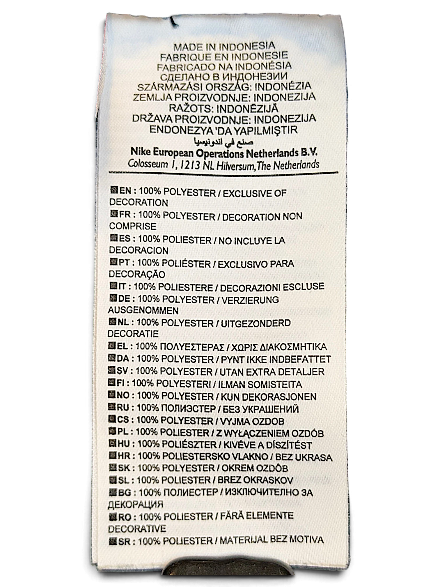 JAKE & IPI Nike track pants care label showing 100% polyester composition in multiple languages