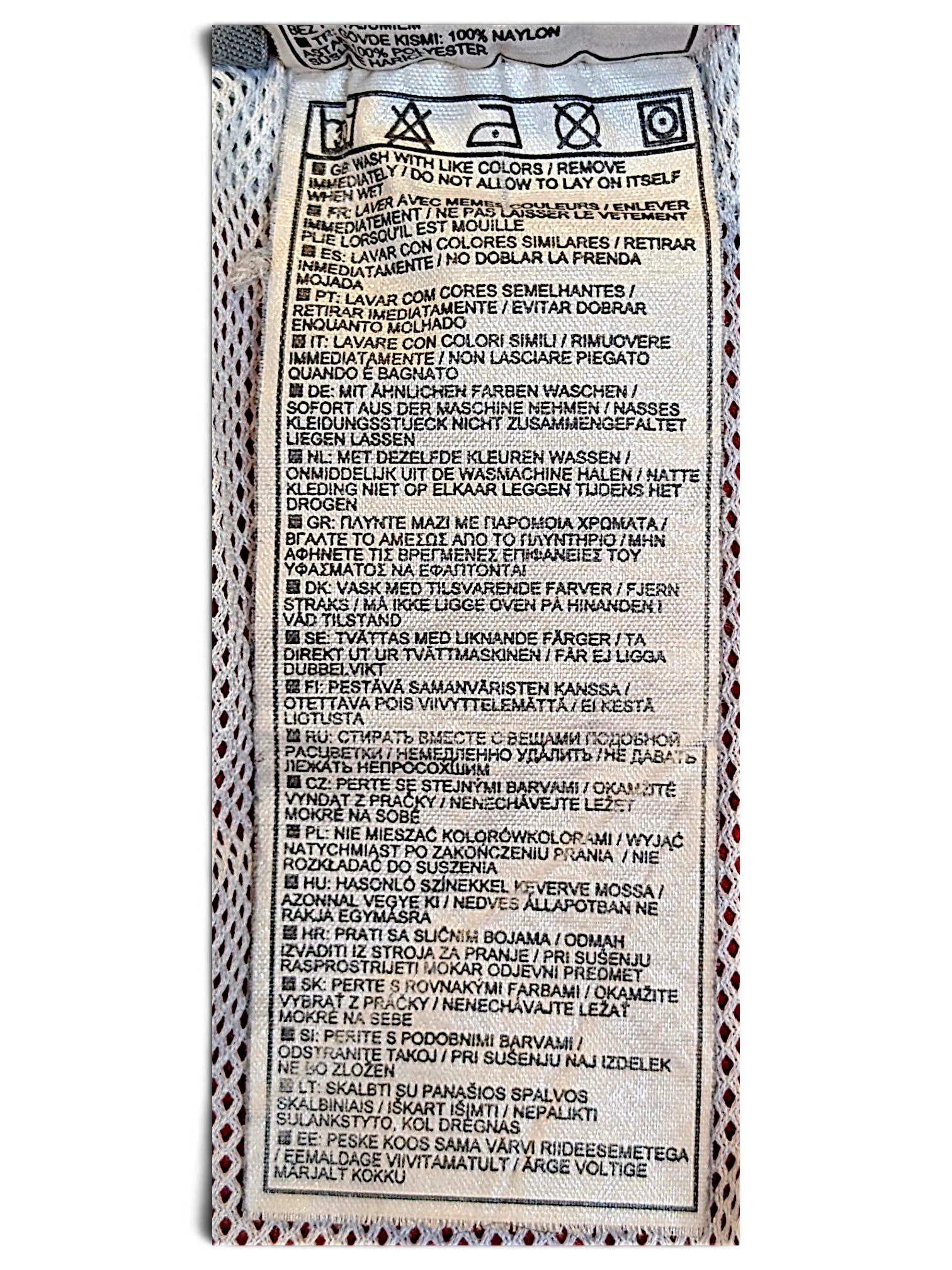 JAKE & IPI Nike track pants care label showing washing instructions in multiple languages on white fabric