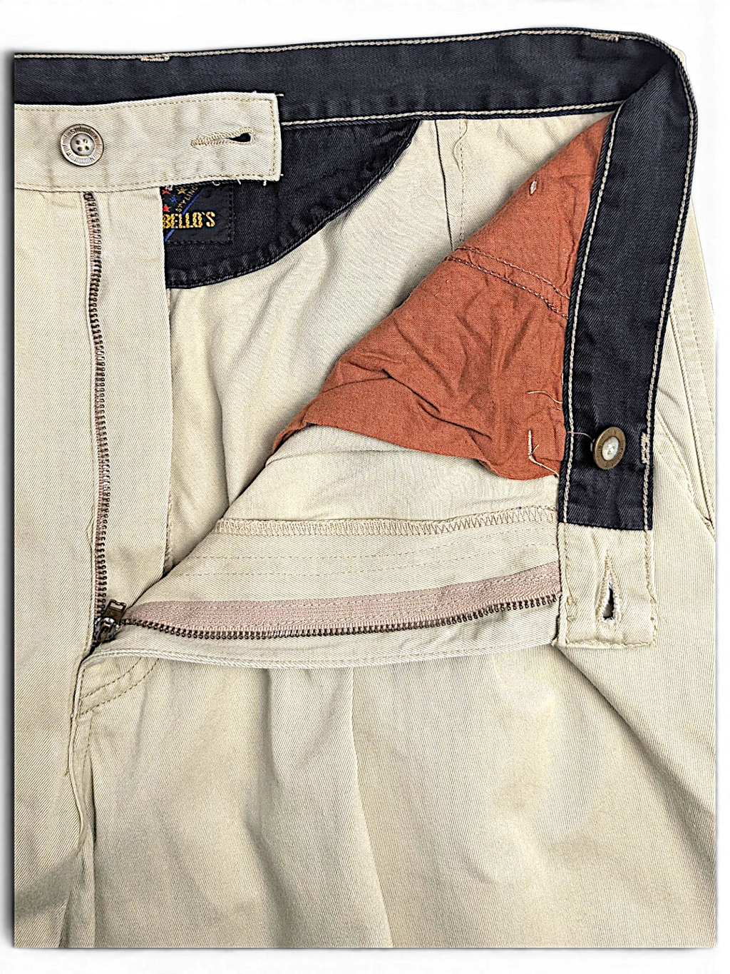 JAKE & IPI Portobello’s beige pleated trousers featuring a dark navy waistband and button fly detail.