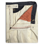 JAKE & IPI Portobello’s beige pleated trousers featuring a dark navy waistband and button fly detail.