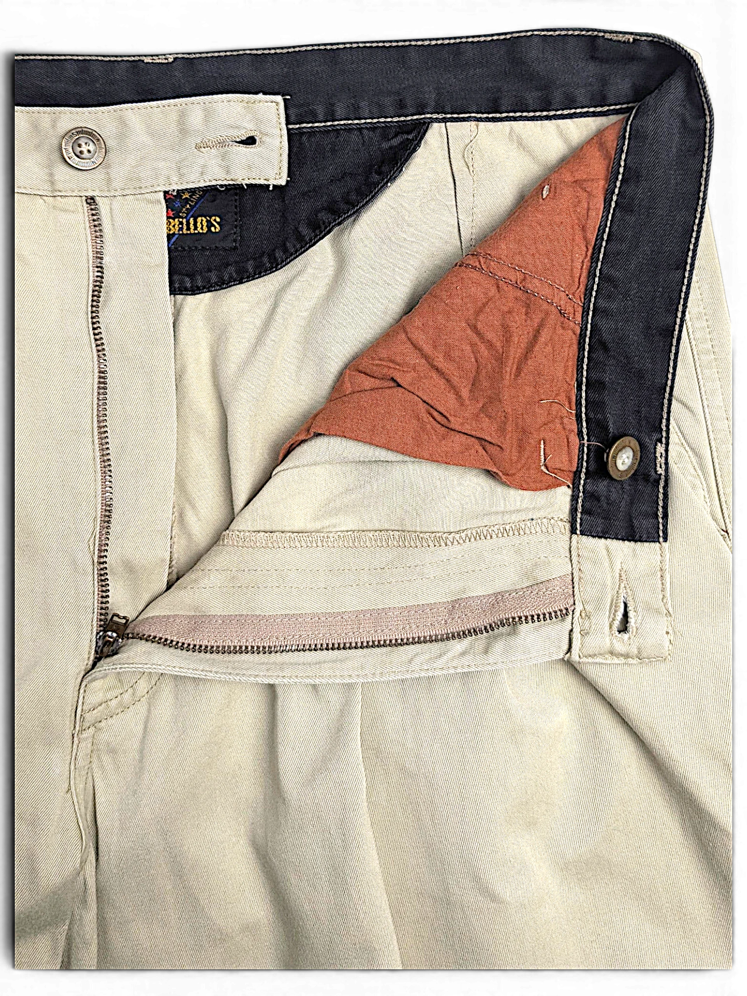 JAKE & IPI Portobello’s beige pleated trousers featuring a dark navy waistband and button fly detail.