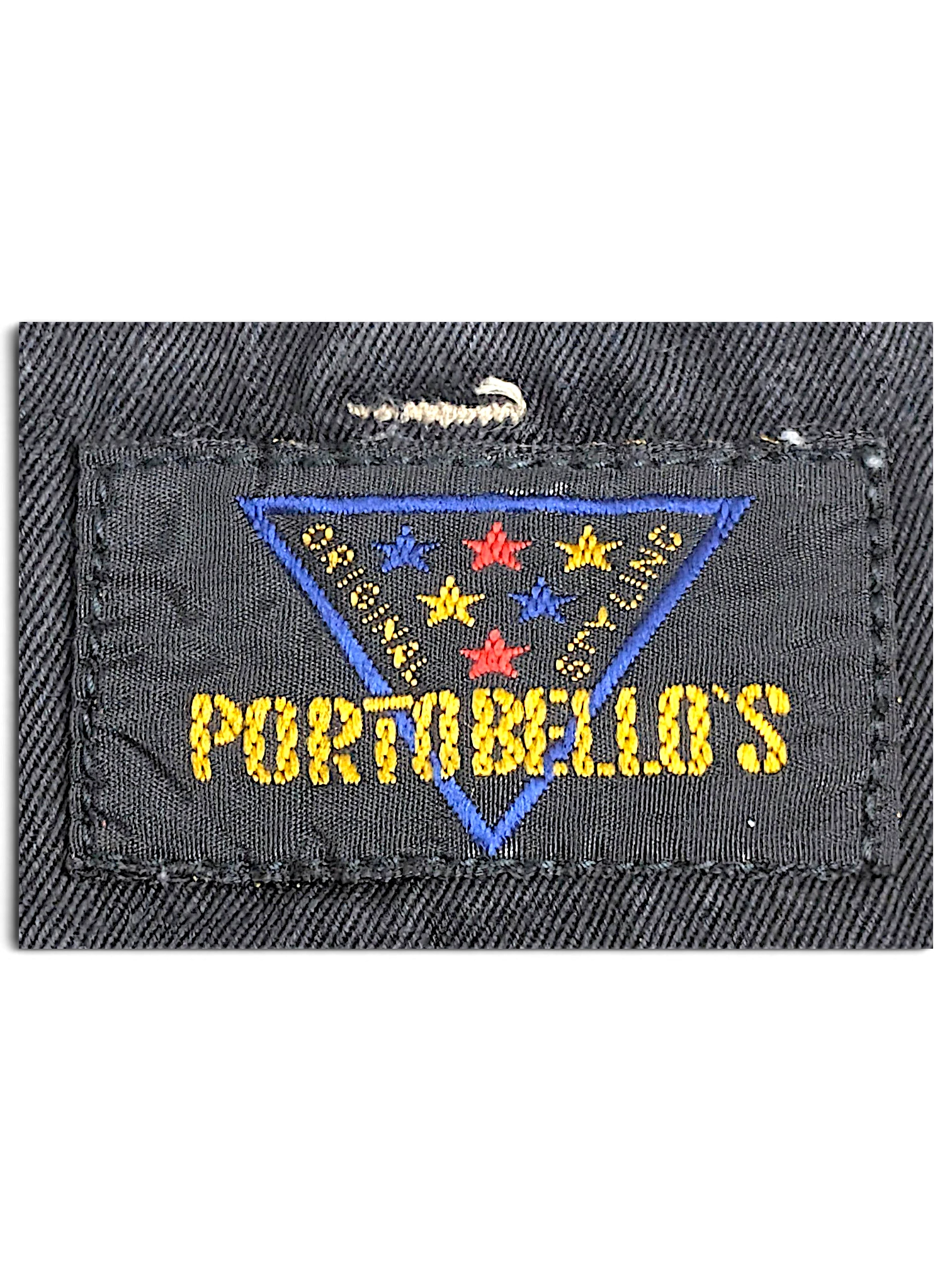 JAKE & IPI Portobello’s clothing brand label featuring a blue triangle with colorful stars on a black fabric background