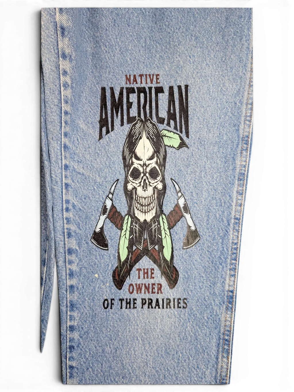 JAKE & IPI light wash denim jeans featuring a Native American skull and tomahawk graphic print on the leg.
