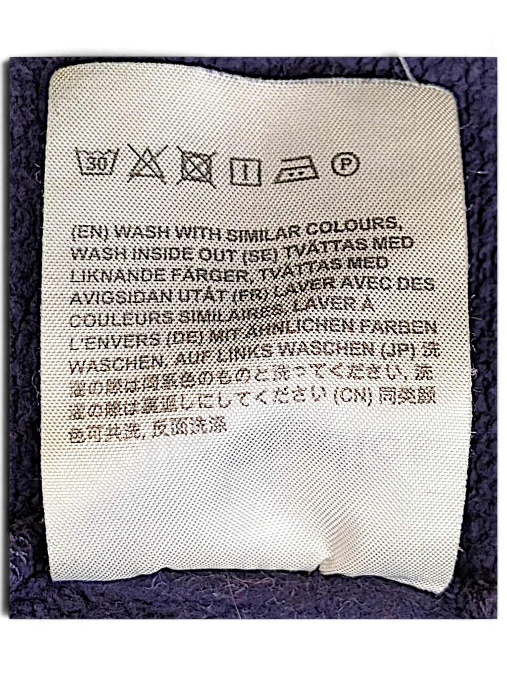 JAKE & IPI purple IBE Acne College sweatshirt care label with washing instructions in multiple languages