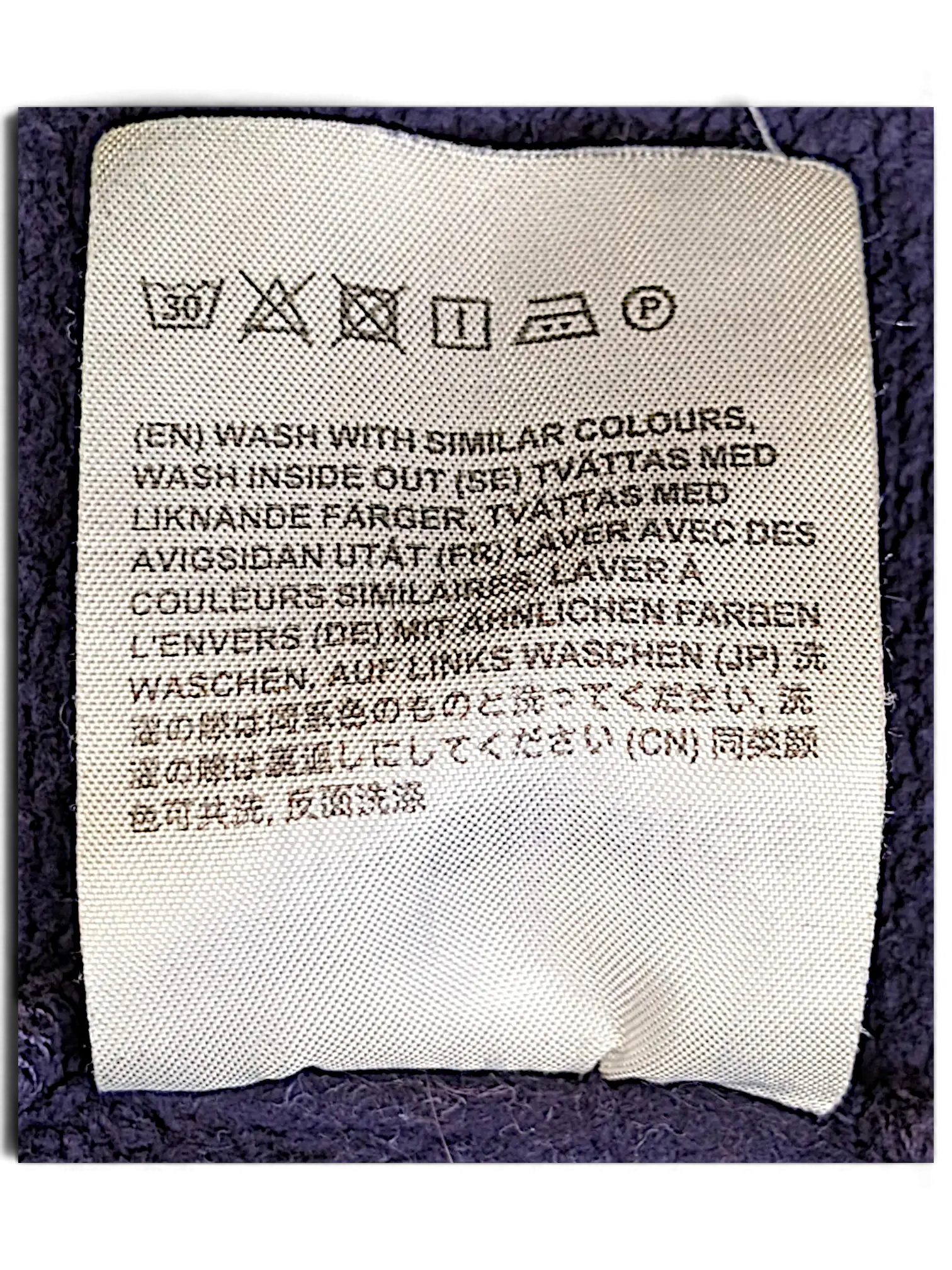 JAKE & IPI purple IBE Acne College sweatshirt care label with washing instructions in multiple languages