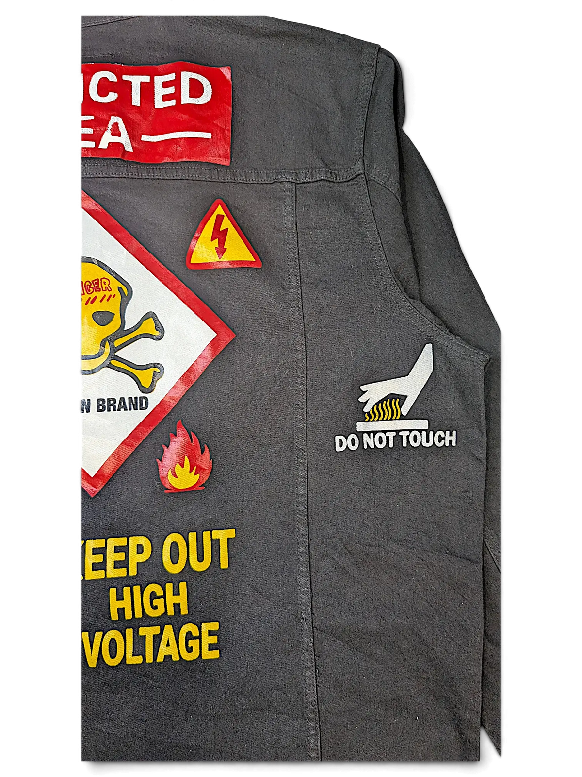 JAKE & IPI Reason denim jacket in charcoal grey featuring various hazard warning patches and graphic prints.