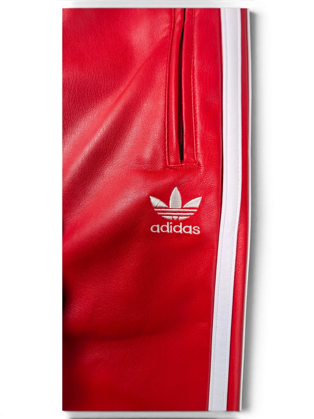 JAKE & IPI red Adidas leather pants featuring white side stripes and an embroidered white trefoil logo.