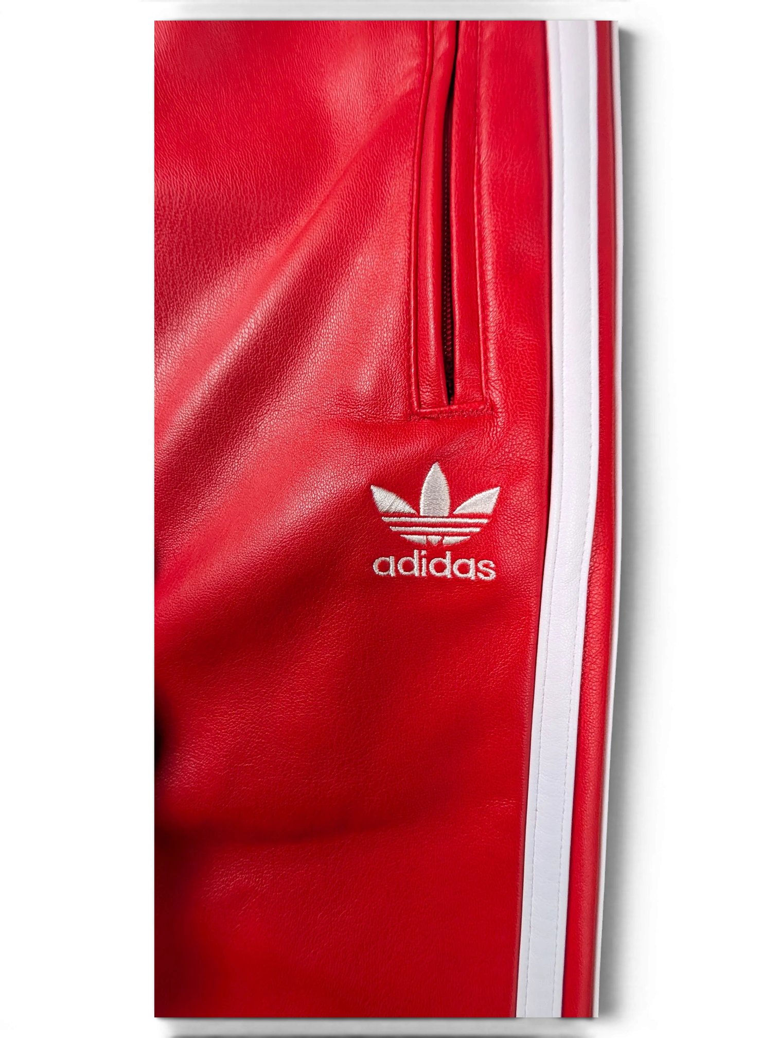 JAKE & IPI red Adidas leather pants featuring white side stripes and an embroidered white trefoil logo.