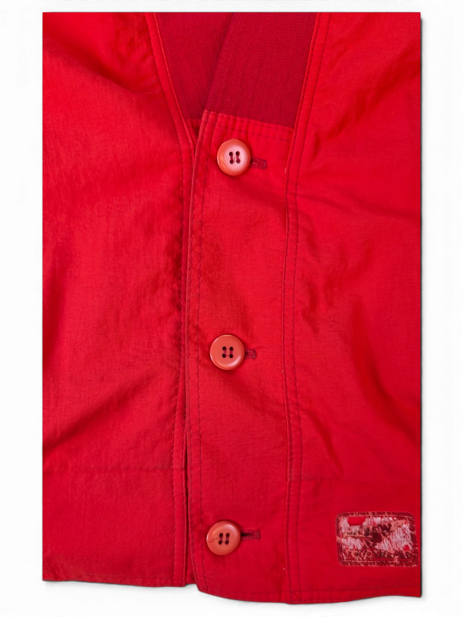 Close-up of a red JAKE & IPI IBE Toyota club button-up shirt featuring matching red buttons and a textured patch.