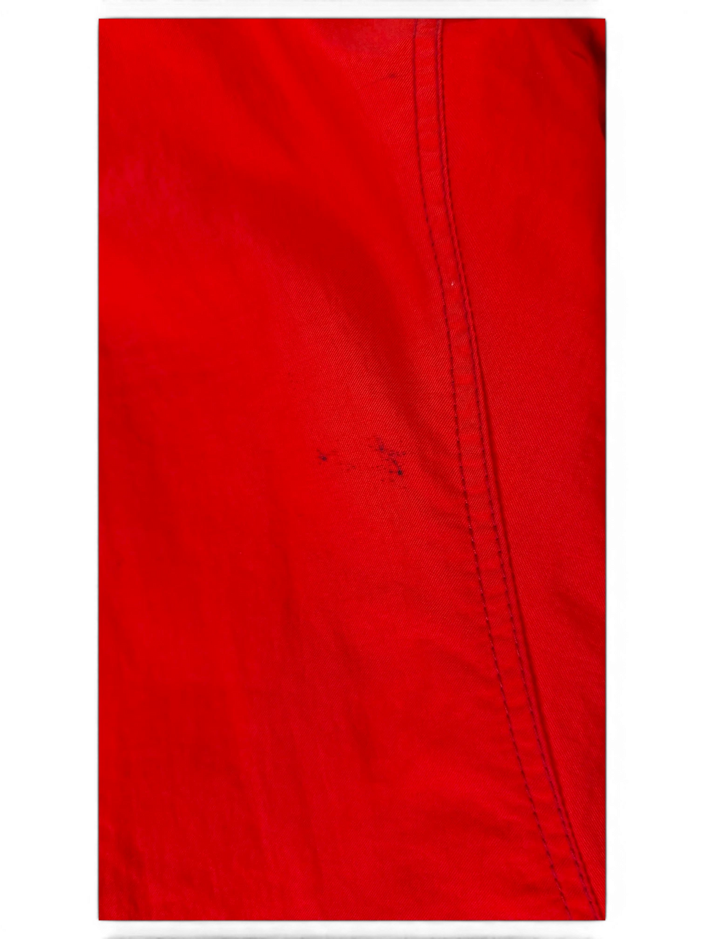 Close-up of JAKE & IPI red fabric from the IBE Toyota club clothing collection with visible stitching detail.