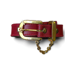 JAKE & IPI red leather belt featuring a polished gold buckle and decorative gold chain detail held in a hand.