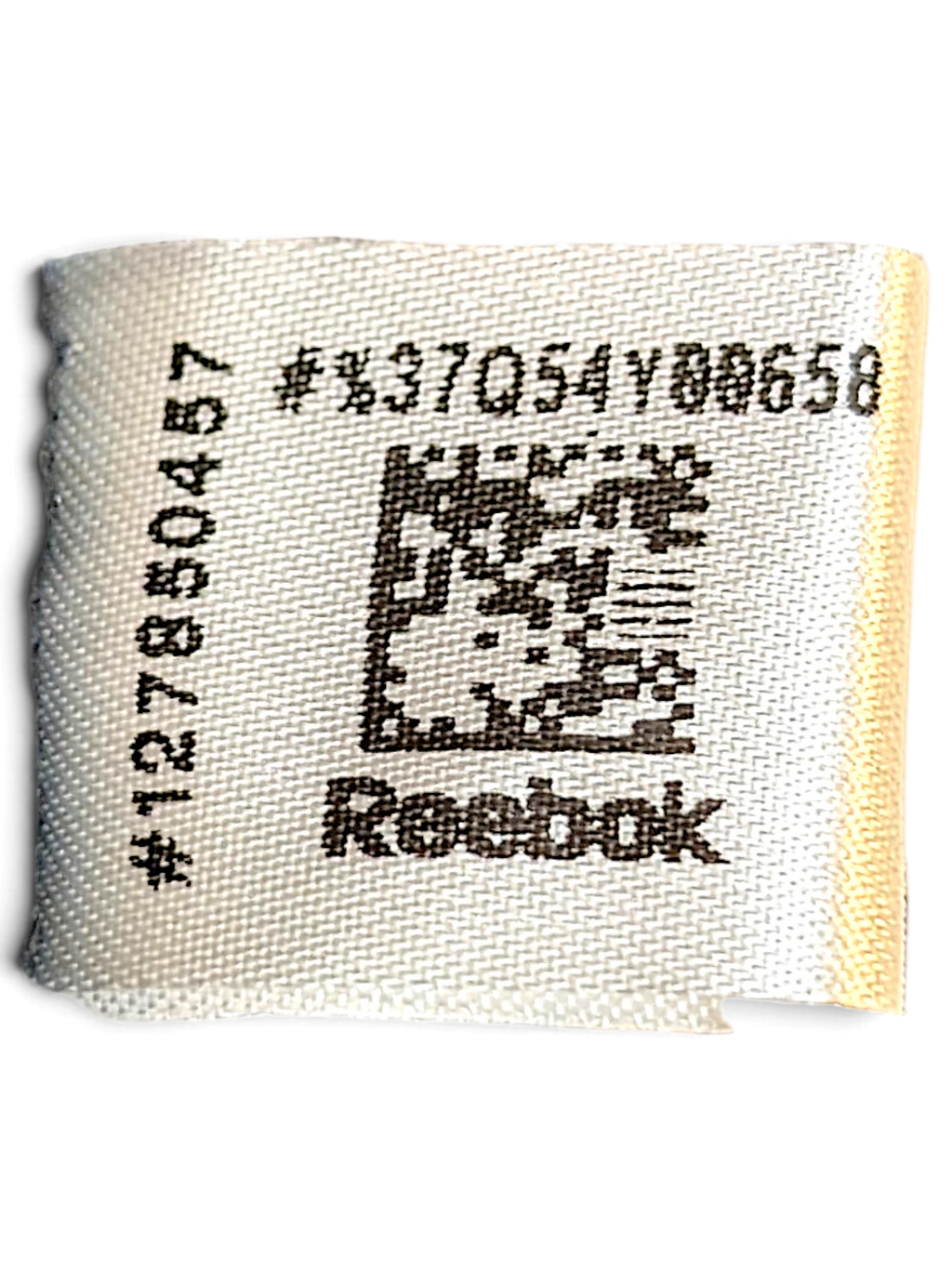 JAKE & IPI Reebok clothing care label with product code and QR code on white fabric