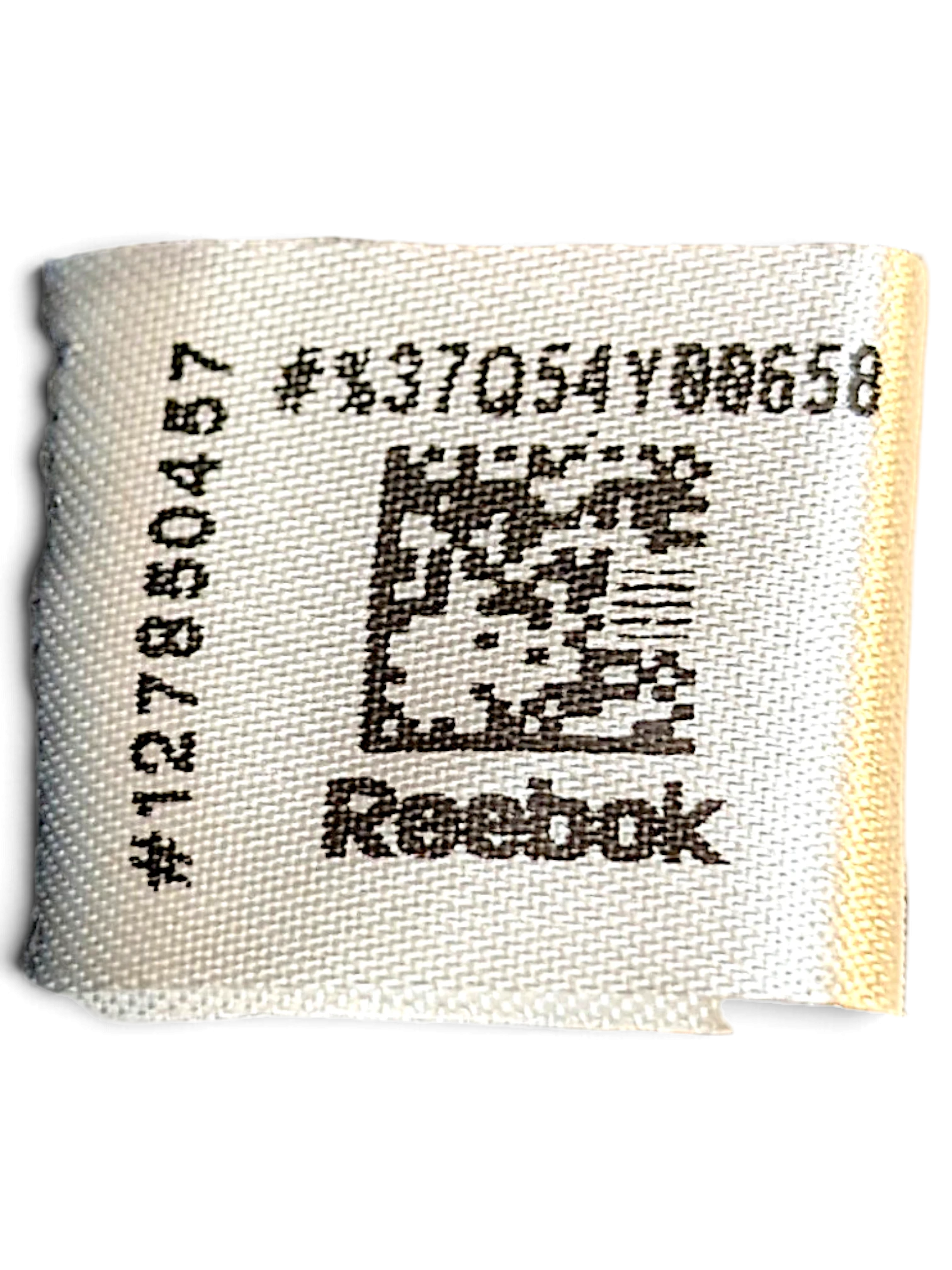 JAKE & IPI Reebok clothing care label with product code and QR code on white fabric