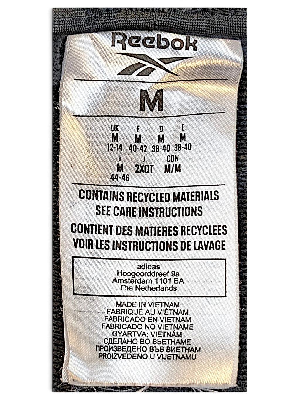 JAKE & IPI Reebok track pants size M clothing label showing recycled materials and manufacturing details