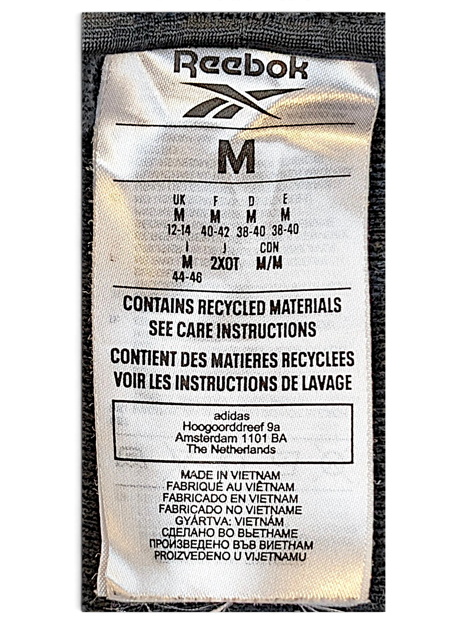 JAKE & IPI Reebok track pants size M clothing label showing recycled materials and manufacturing details