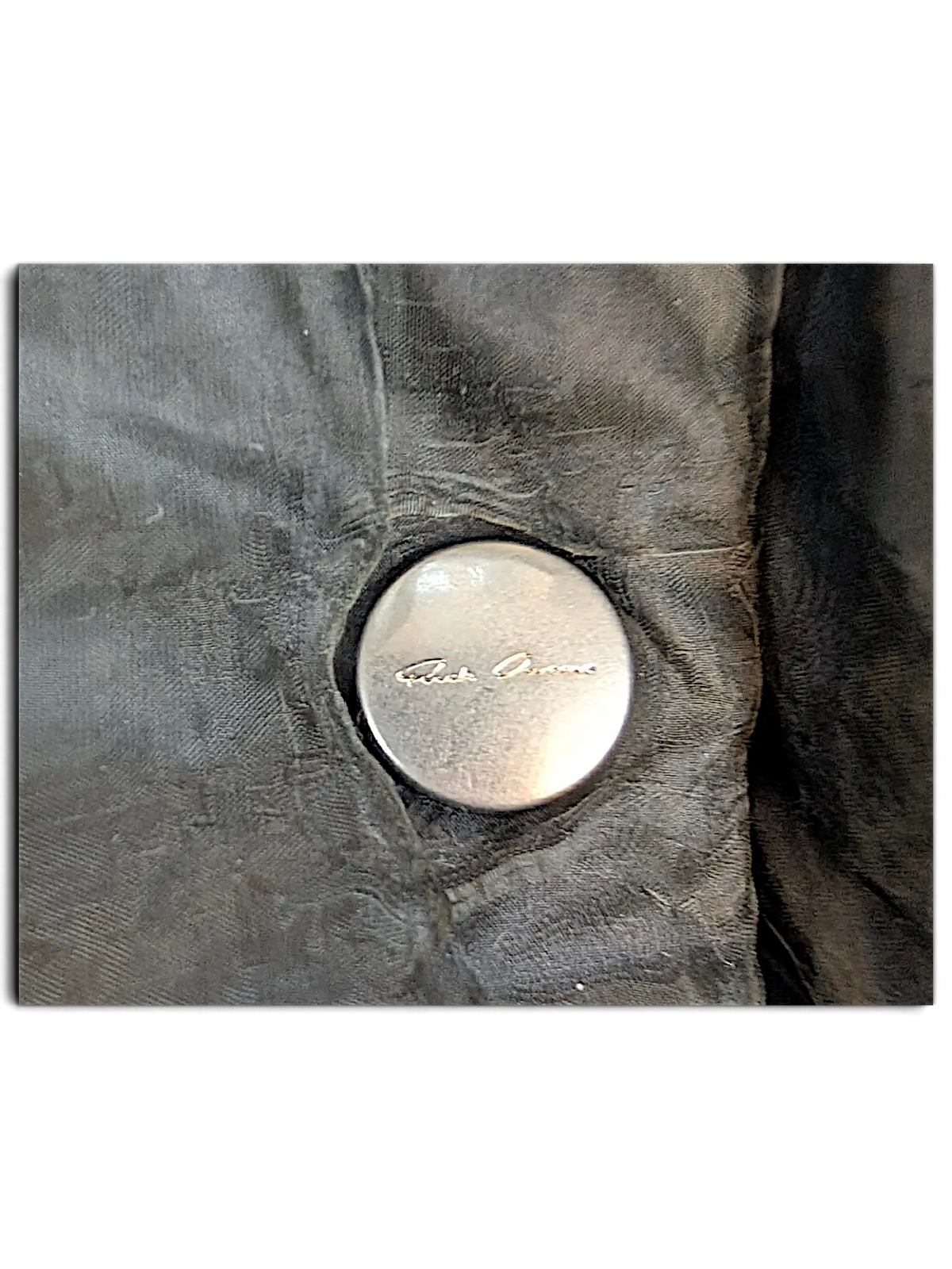 JAKE & IPI Rick Owens bomber jacket featuring a silver metallic button with engraved branding on dark fabric