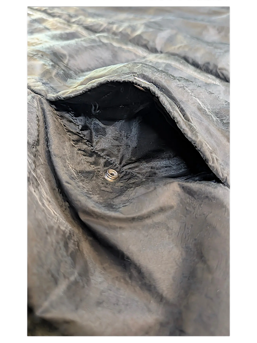 Close-up of a black JAKE & IPI Rick Owens bomber jacket pocket with a metallic snap button closure