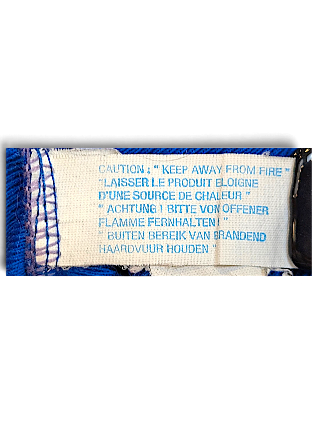 JAKE & IPI Rucanor track pants care label with multilingual fire safety warning text on a royal blue fabric background