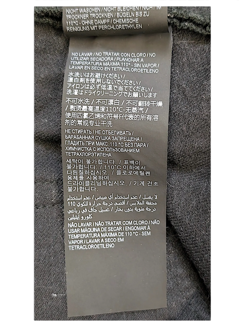 JAKE & IPI Saint Laurent jeans care label with multi-language washing instructions on black fabric