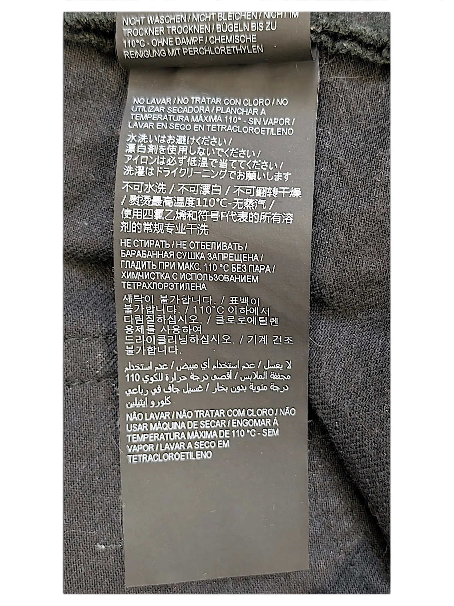 JAKE & IPI Saint Laurent jeans care label with multi-language washing instructions on black fabric