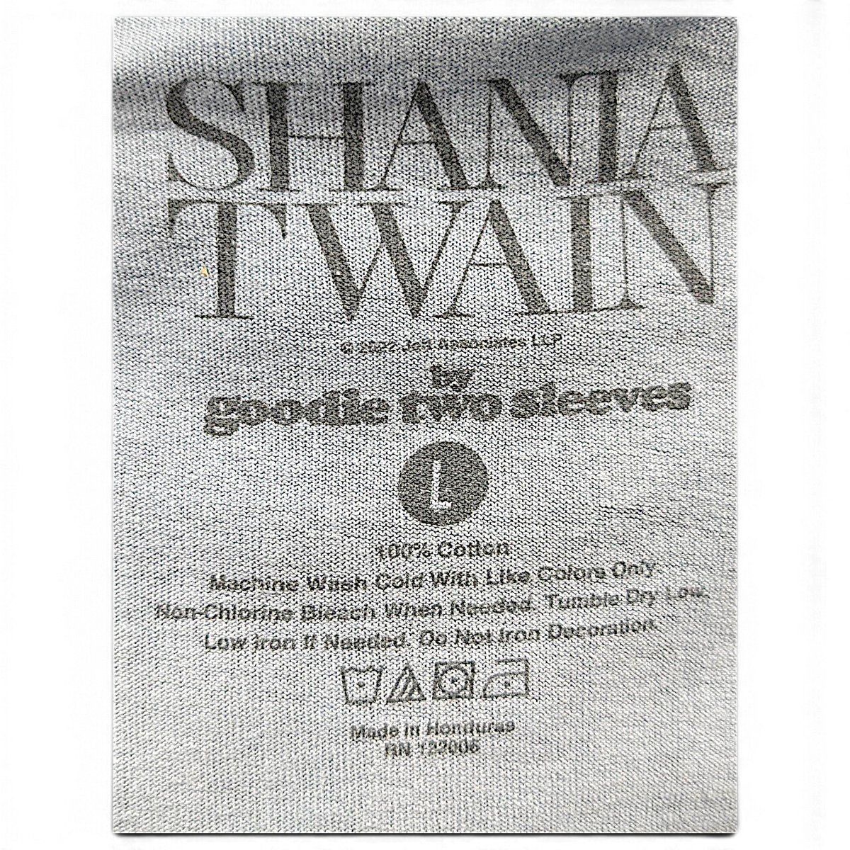 JAKE & IPI Goodie Two Sleeves Shania Twain -t-paidan kokolappu, jossa lukee koko L ja 100 % puuvillaa.