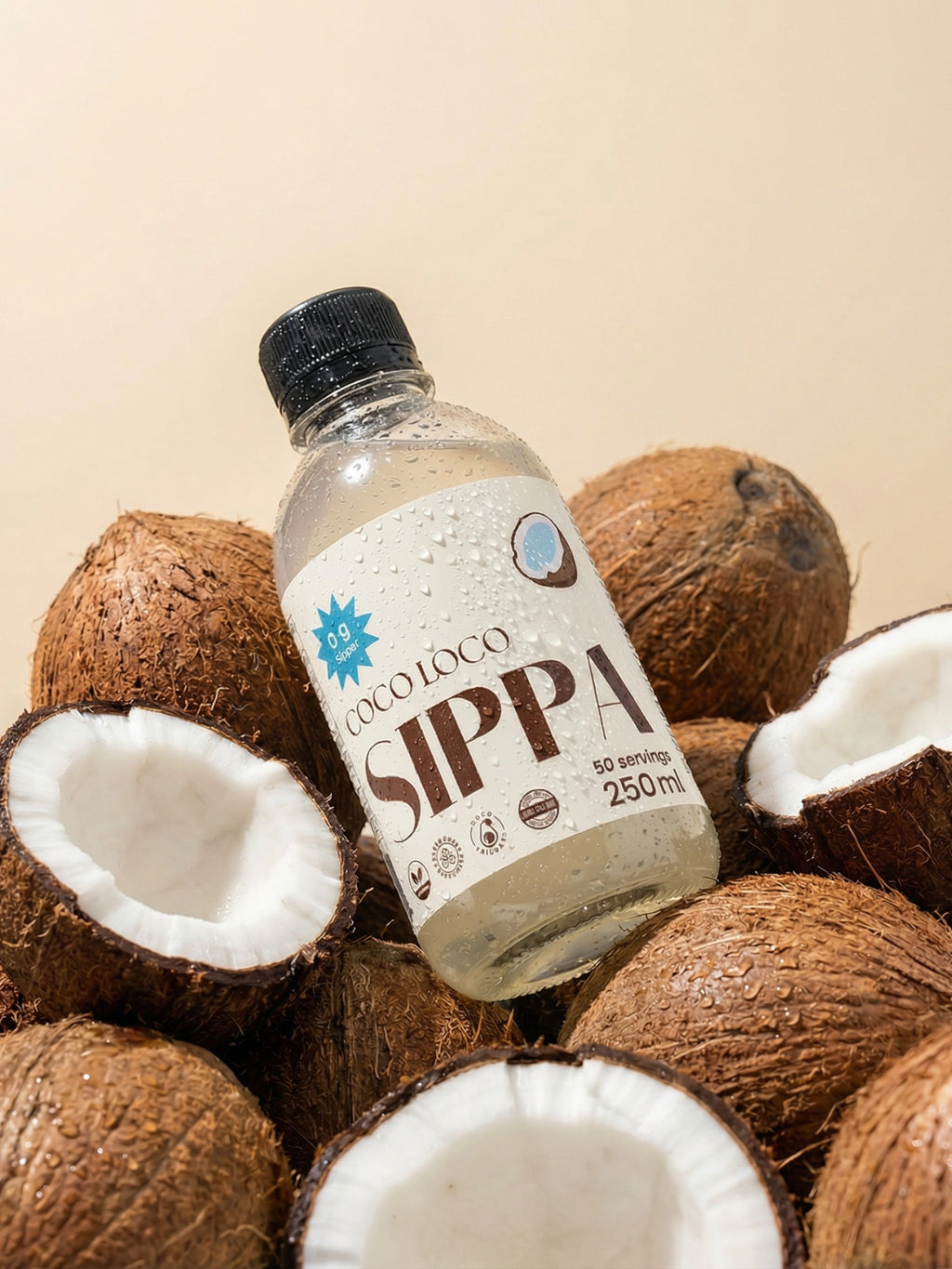 JAKE & IPI SIPPA Coco Loco coconut water bottle surrounded by fresh halved coconuts on a beige background