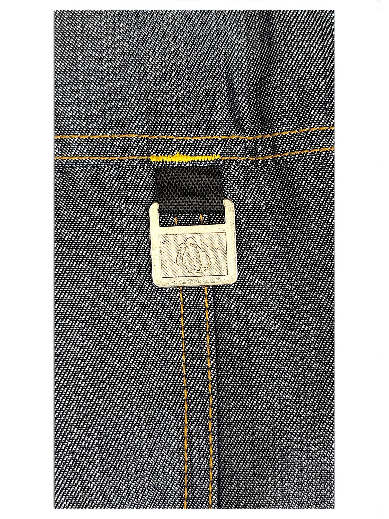 JAKE & IPI Southpole dark denim jacket detail featuring a branded metal hardware tag with contrast yellow stitching.