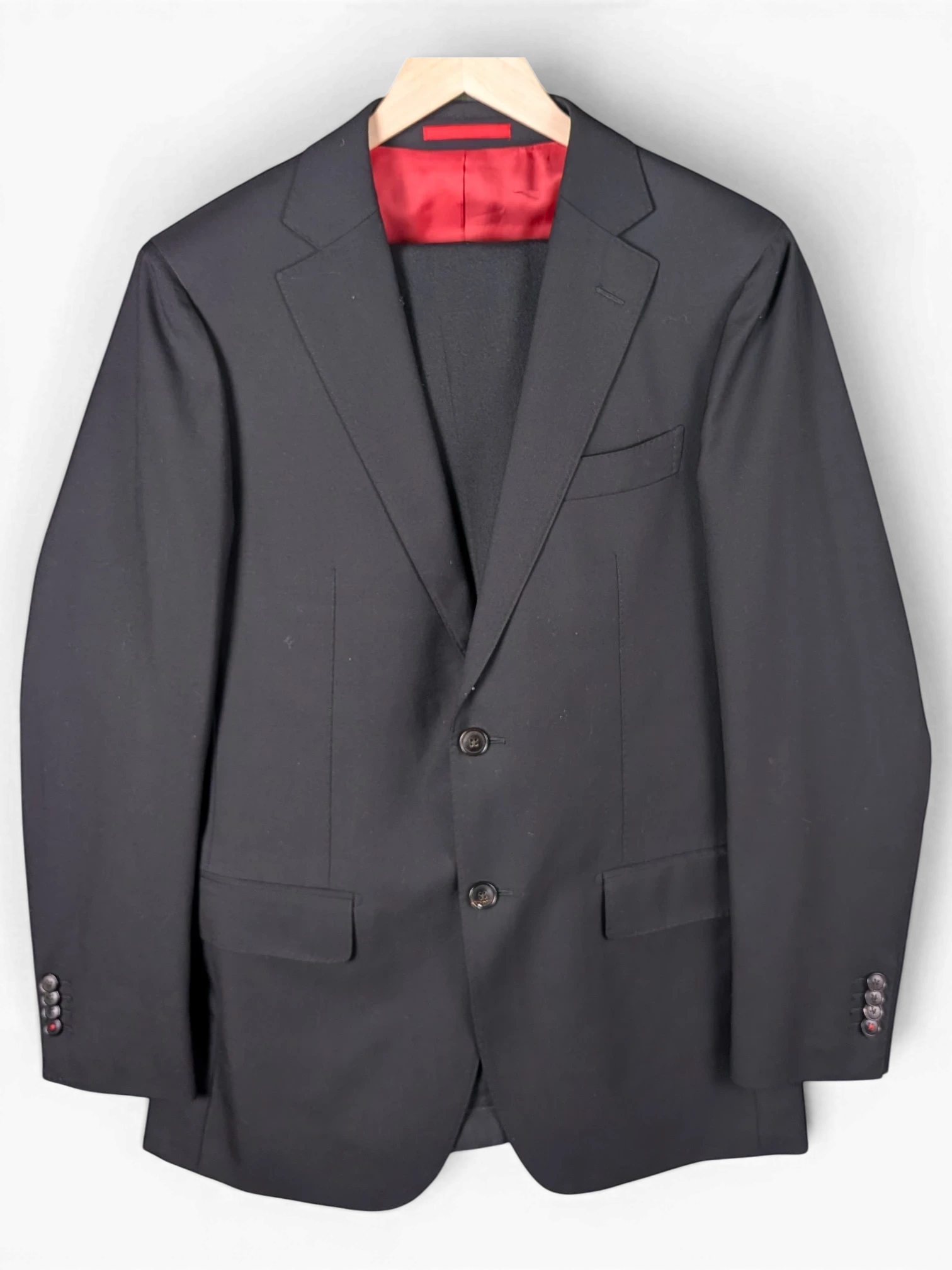 JAKE & IPI Suitsupply black suit jacket with a vibrant red interior lining and two-button closure.