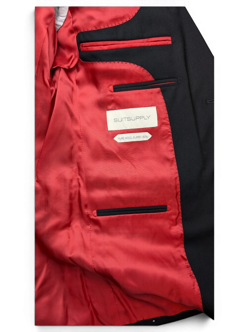 JAKE & IPI Suitsupply black suit jacket interior with vibrant red lining and Super 150s pure wool label