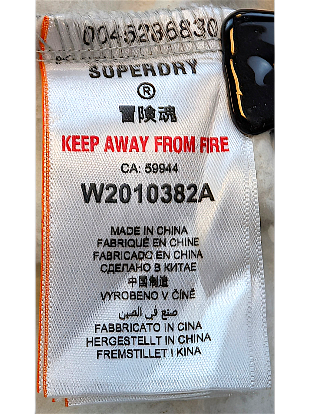 JAKE & IPI Superdry College garment care label with manufacturing details and safety warnings on white fabric
