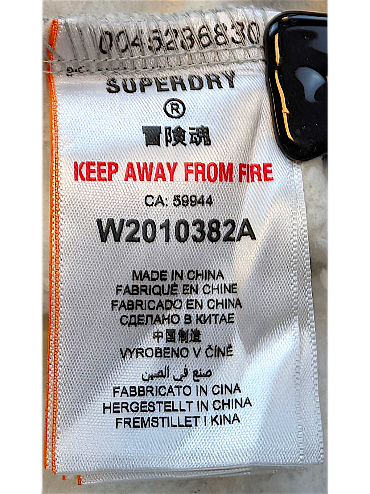 JAKE & IPI Superdry College garment care label with manufacturing details and safety warnings on white fabric