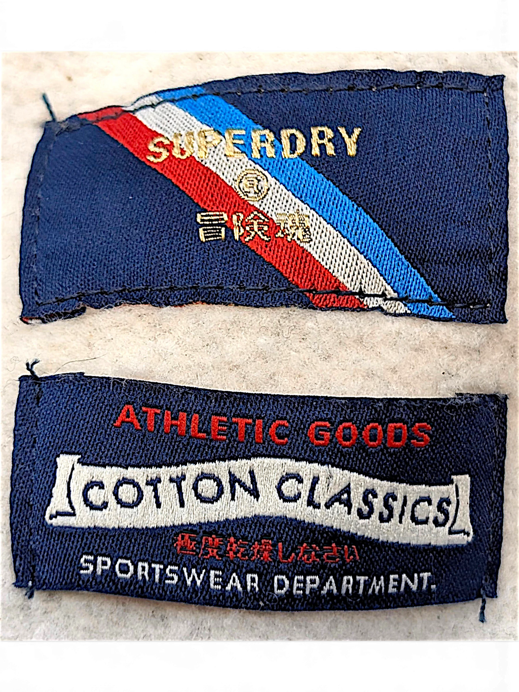JAKE & IPI Superdry College sweatshirt interior brand and care labels with red, white, and blue diagonal stripe