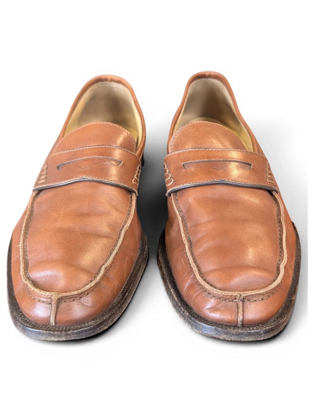 JAKE & IPI tan leather penny loafers with classic moccasin stitching on a dark wooden surface