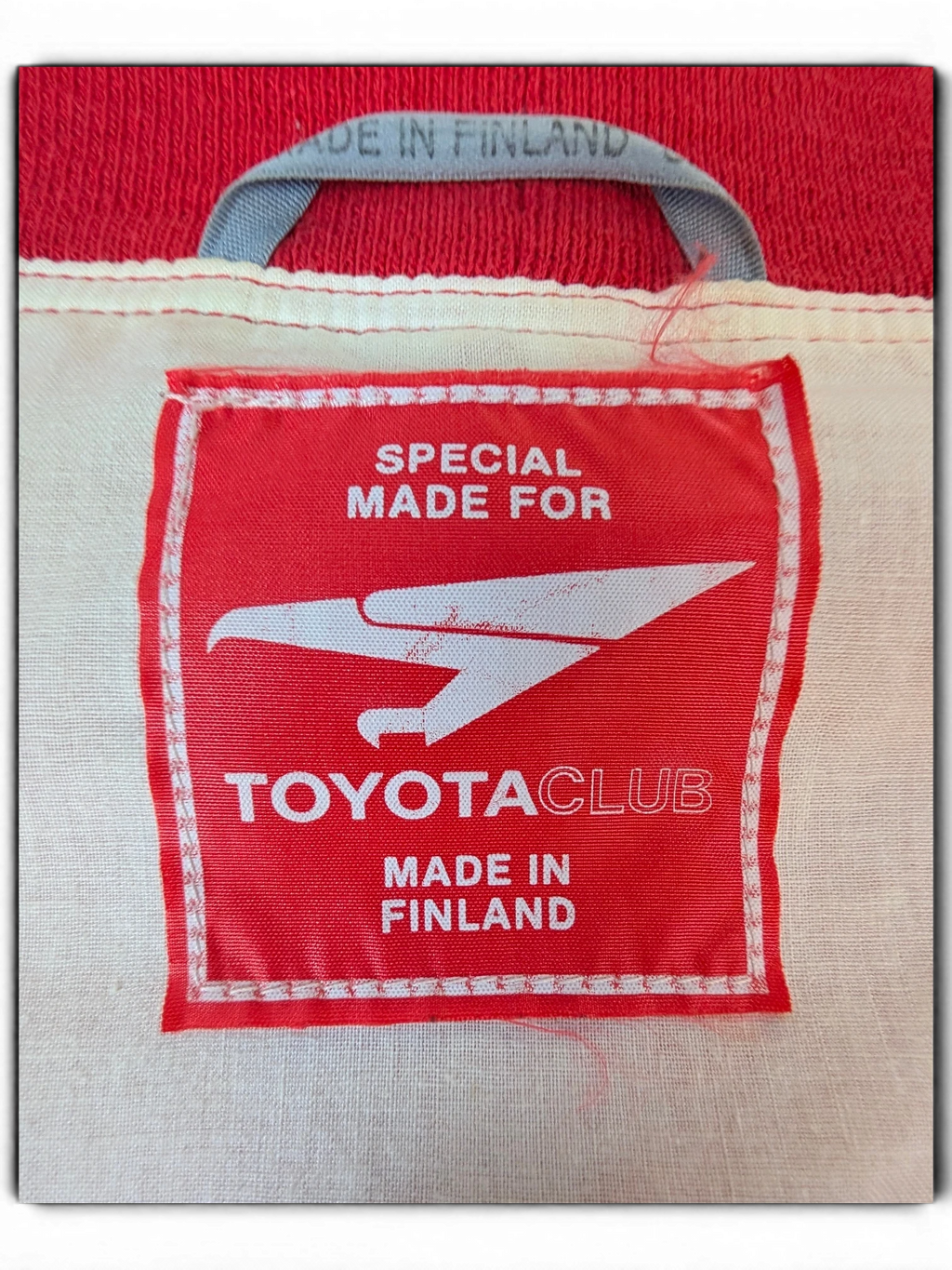 JAKE & IPI red Toyota Club clothing label with white eagle logo and Made in Finland text
