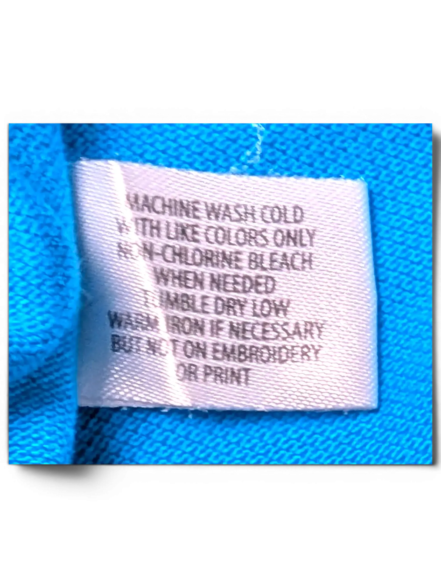 JAKE & IPI turquoise U.S. Polo Assn. shirt care label with washing instructions on cotton fabric