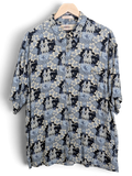 JAKE & IPI vintage 90s Campia Hawaiian shirt in blue with hula dancer and hibiscus floral print on a wooden hanger