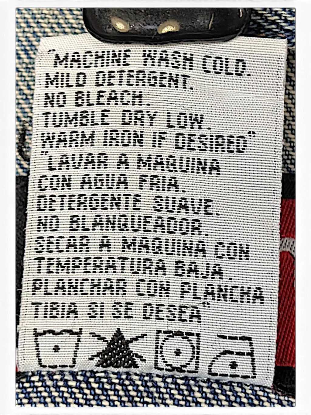 JAKE & IPI Wrangler Hero denim jacket care label with washing instructions in English and Spanish on blue denim